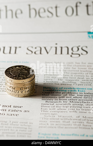 Close up of English money pound coins on page of financial newspaper business finance concept