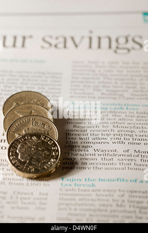 Close up of English money pound coins on page of financial newspaper business finance concept