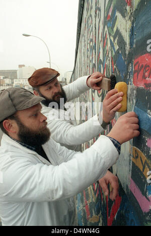 Restaurators Ullrich and Eckard Kobelius (front) from Potsdam work on the concrete blocks of the section of the Berlin Wall in Friedrichshain in Berlin, Germany, in 1991. The paintings on this section, the East Side Gallery, have to be protected  from the weather conditions. Photo: Bernd Settnik Stock Photo