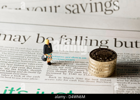 Close up of Toy tiny small figure of a woman stood on page of financial newspaper business finance concept falling interest rate rates Stock Photo