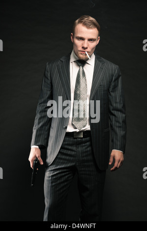 Man in suit shooting with gun. Smoking cigarette. Studio shot. Stock Photo