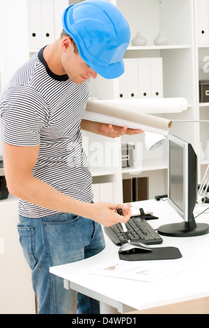 Young male architect looking at plans in the office Stock Photo