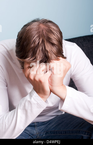 young man with his head in his hands Stock Photo