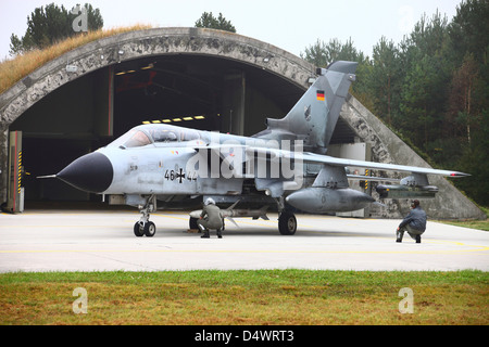 Ground crew conducting pre-flight-checks on a German Tornado ECR, armed with an HARM missile, in front of its shelter Stock Photo