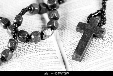 Rosary beads and cross lying on an open page of the bible isolated on ...