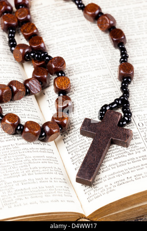 Rosary beads and cross lying on an open page of the bible. Stock Photo