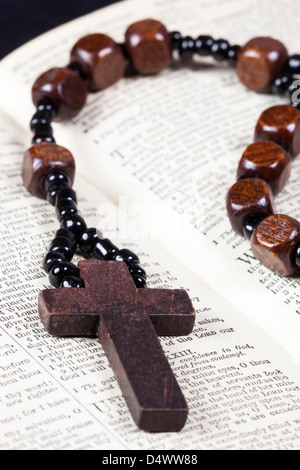 Rosary beads and cross lying on an open page of the bible. Stock Photo