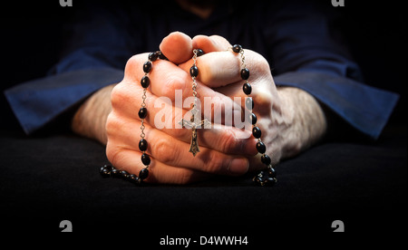 Hands holding rosary beads and cross while praying. Stock Photo