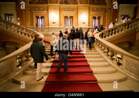 Budapest Opera House main staircase interior in Hungary, group of tourists on tour climbing the stairs. Stock Photo