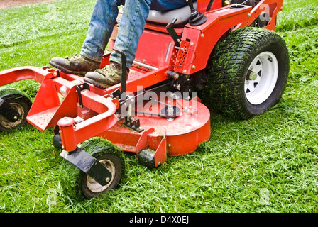 Man on a riding lawn mower that has grass stuck to the wheels. Spring and summer outdoor maintenance. Stock Photo