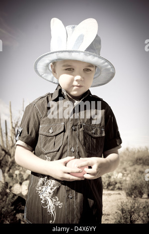 A five year old boy with autism takes a moment to himself while hunting for plastic Easter eggs in the desert. Stock Photo