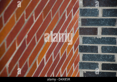 Two brick walls meeting in a gray, black, red and orange, brick wall background texture with contemporary clean lines Stock Photo