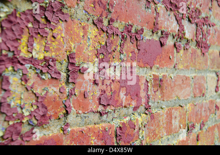 Gritty urban background red brick wall texture with peeling dark red paint and yellow splatters Stock Photo