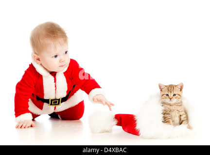 christmas baby reaching out hand for cat in a santa claus hat Stock Photo