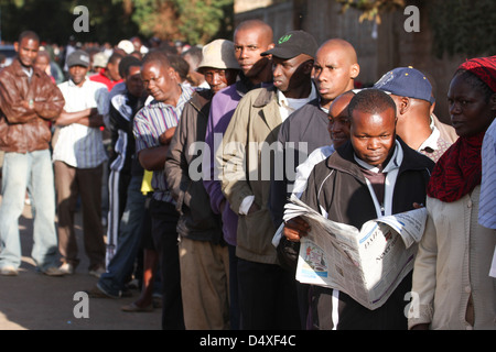 New Kihumbuini Primary School, Nairobi, Kenya - 4 March 2013: A man reads the morning paper whilst queuing to cast hos vote at New Kihumbuini Primary School polling station. © David Mbiyu/Alamy Live News Stock Photo