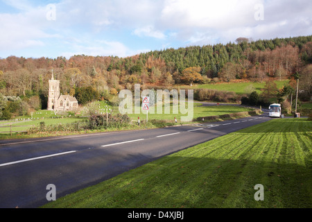 A Webber coach traveling along the A39 at west Quantoxhead, Somerset in England with Saint Etheldreda's Church in the distance Stock Photo