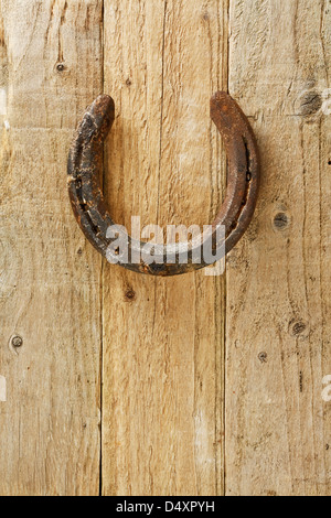 Old rustic horseshoe hanging on door said to bring good fortune and luck according to superstition Stock Photo