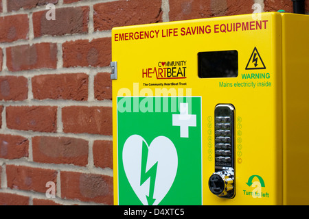 Emergency defibrillator in a bright yellow box on the outside wall of a sports centre Stock Photo