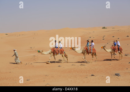 Tourists riding camels in desert, Dubai, United Arab Emirates Stock Photo