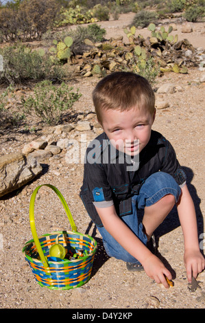 A five year old boy with autism takes a break from hunting for plastic eggs to play with his new animal toys. Stock Photo