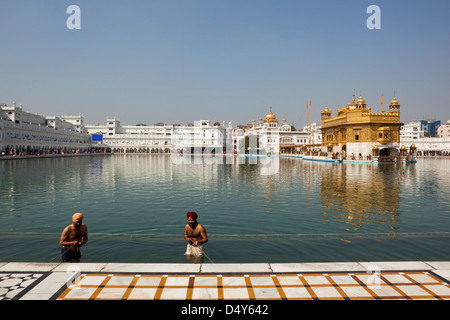 Two Sikh devotees bathing in the sacred Holy Pool at the magnificent Golden Temple in Amritsar Punjab India Stock Photo