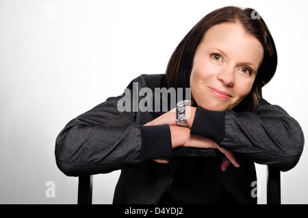 Beautiful brunette smiling. Happy dark haired woman leaning on ladder and smiling. Stock Photo