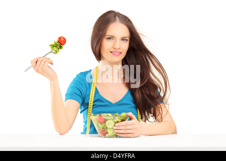 Beautiful young woman with a measuring tape eating salad Stock Photo