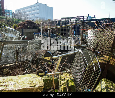 Broken and abandoned shopping trolleys lie piled in a field in Portsmouth England Stock Photo