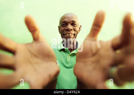 portrait of senior black man with hands and arms open pointing at camera. Green background Stock Photo