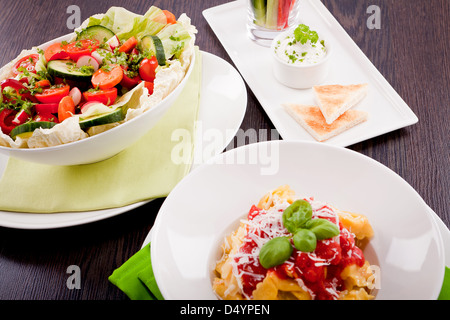collection of different plates with healthy food pasta salad vegetables on wooden table Stock Photo