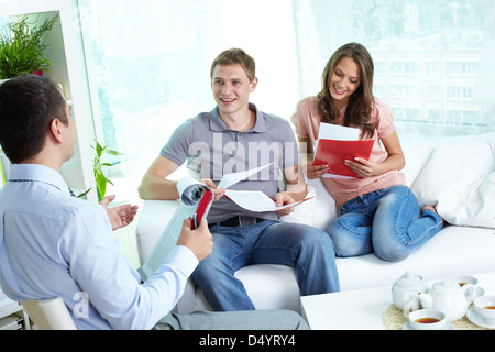 Young family reading insurance contract, their agent advising Stock Photo
