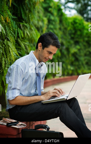 Businessman using a laptop in a park Stock Photo