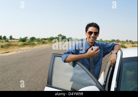 Businessman standing near his car and drinking tea Stock Photo