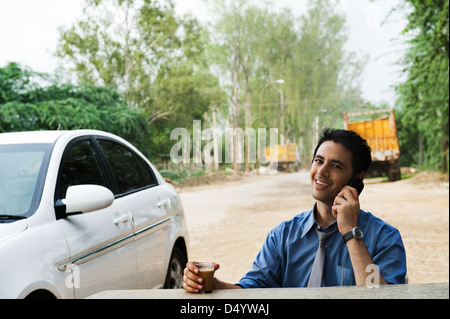 Businessman drinking tea and talking on a mobile phone Stock Photo