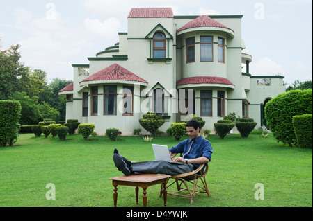 Businessman using a laptop in a garden Stock Photo