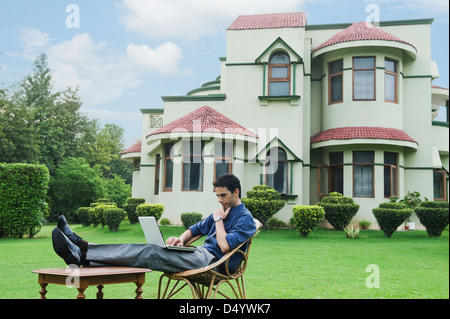 Businessman using a laptop in a garden Stock Photo