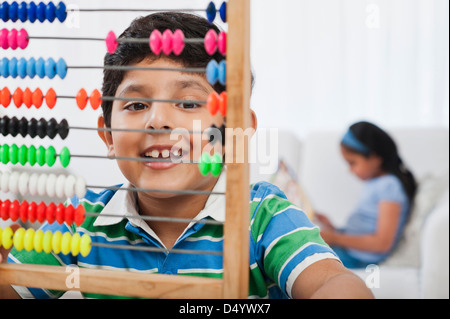 Boy using an abacus with his sister in the background Stock Photo