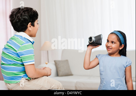 Boy holding a lollipop and his sister filming him with a video camera Stock Photo
