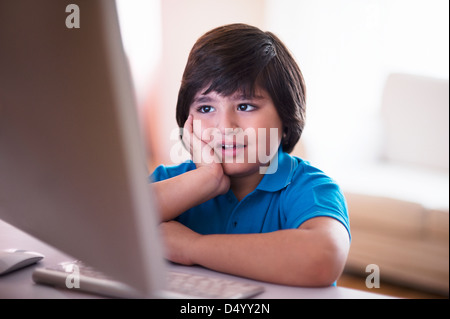 Boy using a desktop computer and thinking Stock Photo