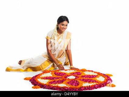South Indian woman making a rangoli of flowers at Onam Stock Photo