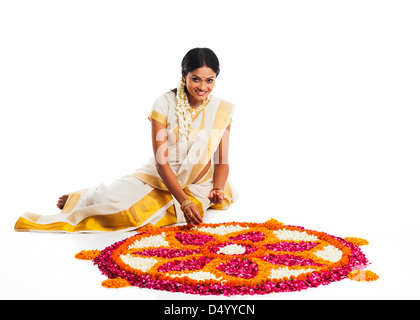 South Indian woman making a rangoli of flowers at Onam Stock Photo