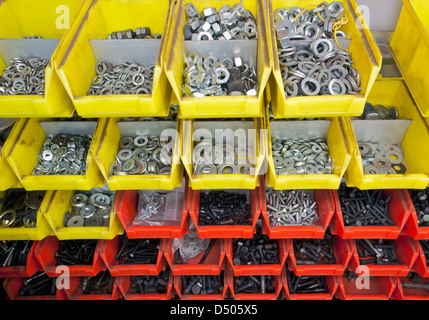 full frame industrial background showing yellow and red boxes filled with lots of various screws and nuts Stock Photo