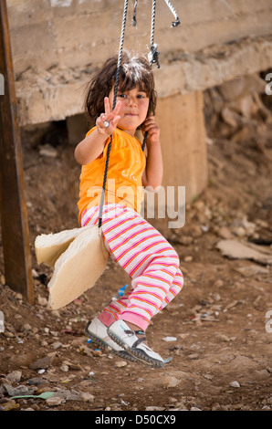 A young Syrian girl on a makeshift wsing make a Victory sign in the King Abdullah refugee camp in Jordan near the Syrian border Stock Photo