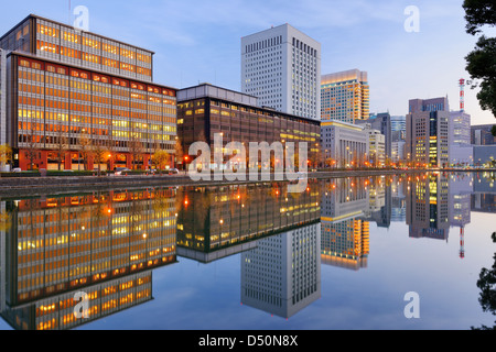 Landmark buildings reflect off the Imperial Palace moat in the Marunouchi district of Tokyo, Japan. Stock Photo