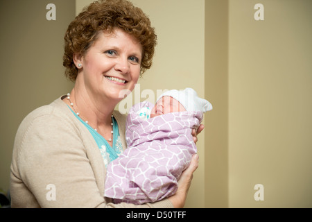 A first-time grandmother holds her newly born infant granddaughter and smiles with happiness. USA. Stock Photo