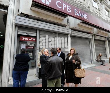 People wait to use the ATM in front of a closed branch of CPB Bank (Cypriot Popular Bank) in Athens, Greece, Giorgos Nikolaidis Stock Photo