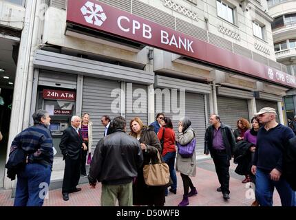 People wait to use the ATM in front of a closed branch of CPB Bank (Cypriot Popular Bank) in Athens, Greece, Giorgos Nikolaidis Stock Photo
