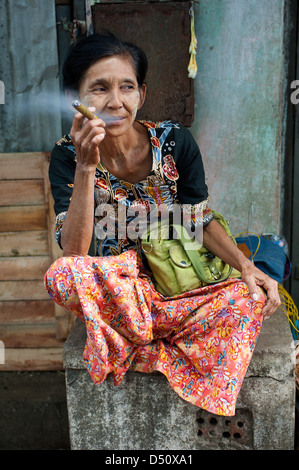 A woman in the Chinese market area of Yangon, Myanmar, relaxes with a cheroot, one of the country's main products. Stock Photo