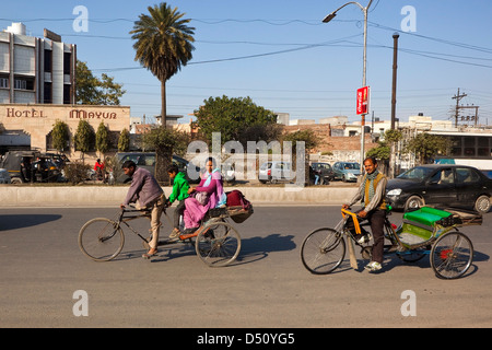 Two cycle rickshaws one with passengers riding along the streets of Amritsar Punjab India Stock Photo