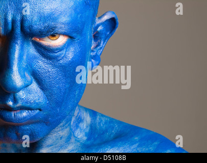 Face of a man painted of blue color with serious expression over isolated background. Stock Photo